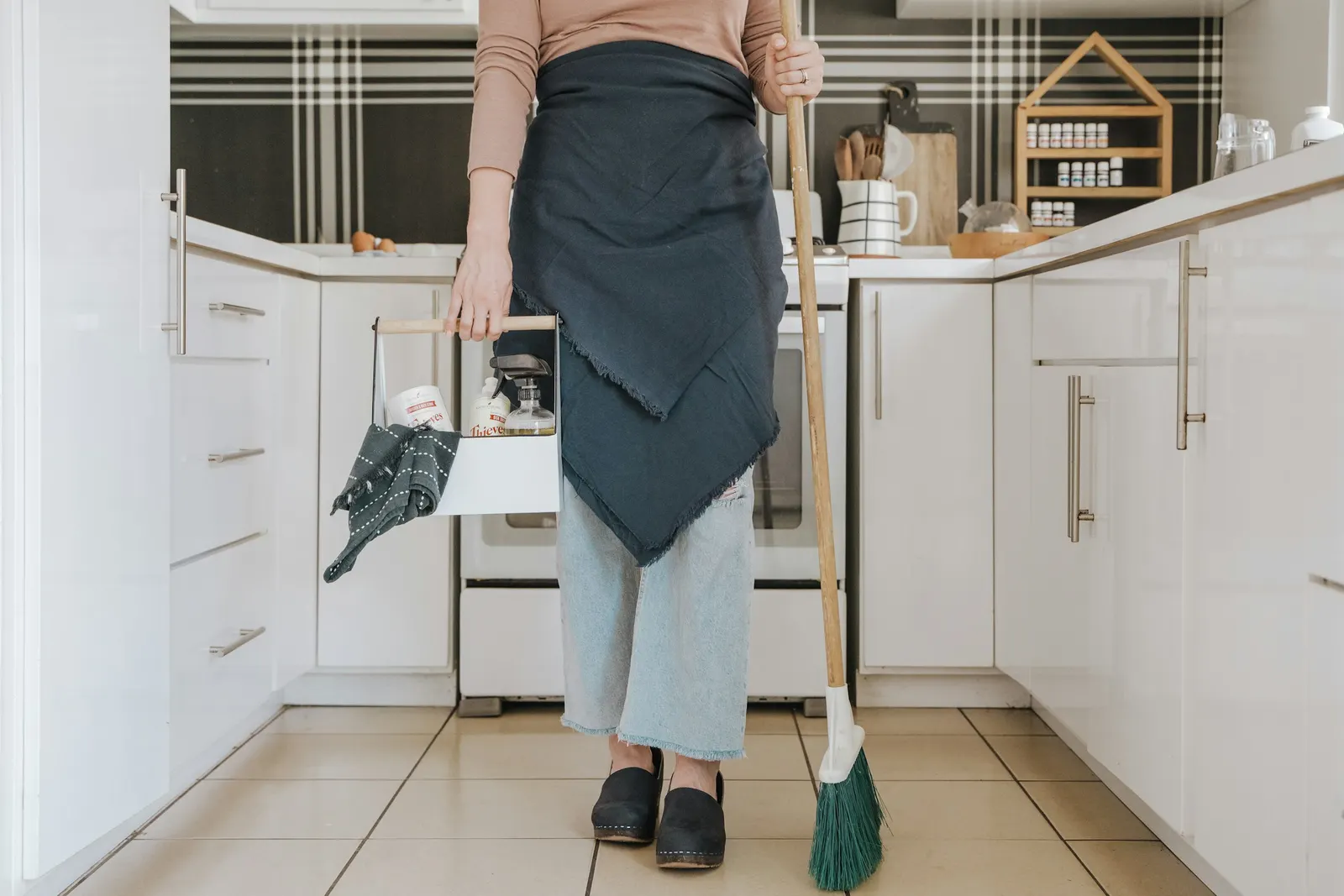A cleaning caddy of supplies and a broom, ready for a routine visit
